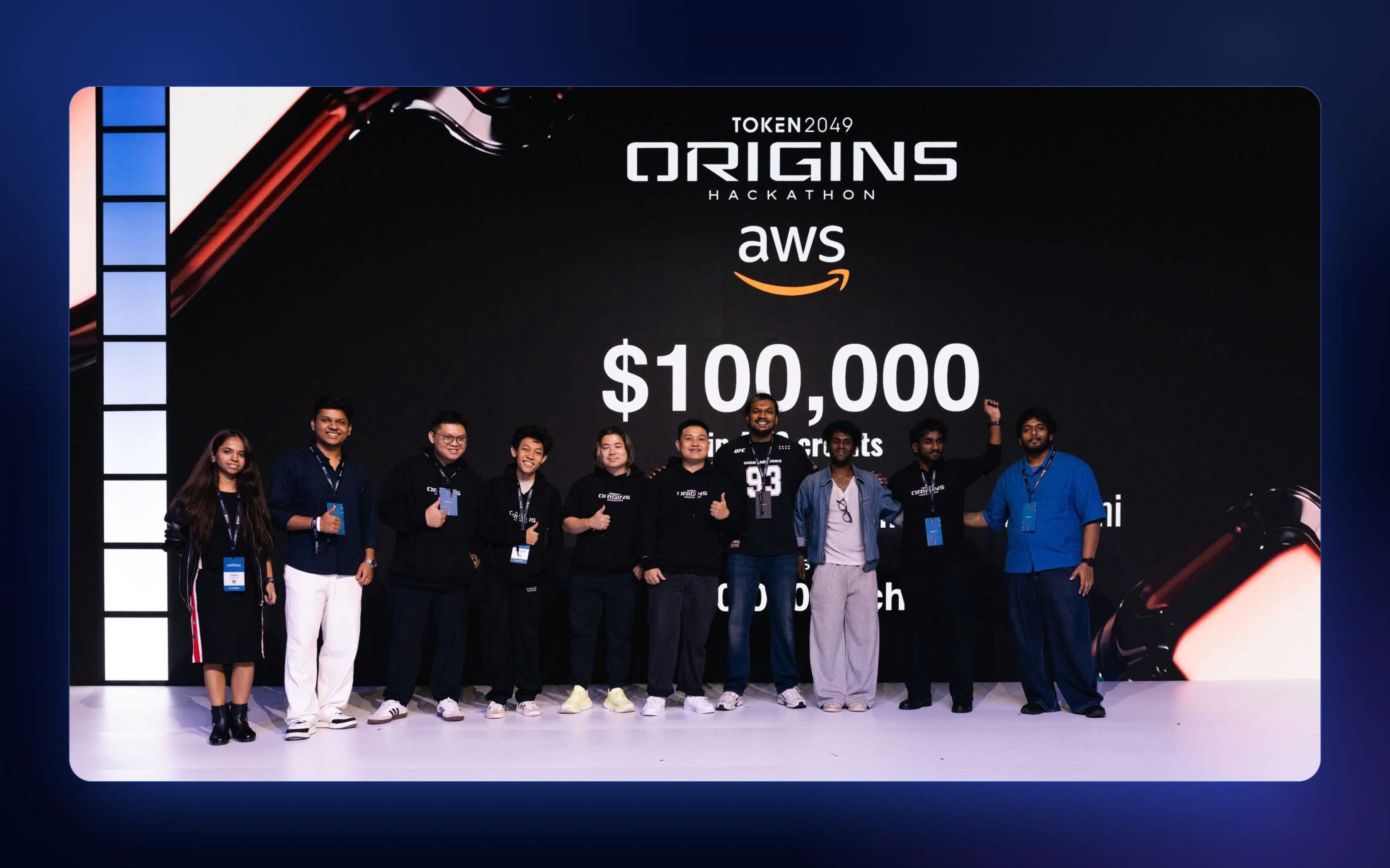 TOKEN2049 Origins Hackathon finalists on stage in front of the AWS prize board